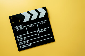 Naklejka premium Black movie clapperboard on yellow background, concept of film production, cinema industry, video content creation, and creative media.