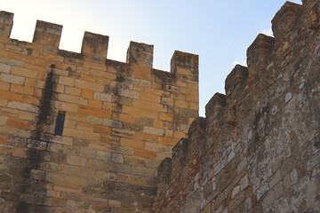 Stone walls of an old castle with battlements at the top