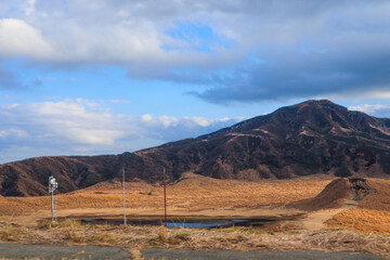 Dramatic Sun Rays Piercing Dark Clouds Over Rolling Volcanic Mountains at Dusk