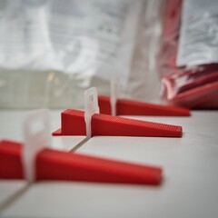 Tile leveling wedges and clips in action during ceramic installation. Macro view of precision tools for smooth, professional flooring. Ideal for DIY, construction, and tutorial visuals.