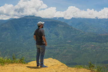Latino man standing at a viewpoint in Barichara Colombia, admiring vast mountains and clouds. freedom, adventure, exploration, travel lifestyle, nature connection, inspiration and mindfulness