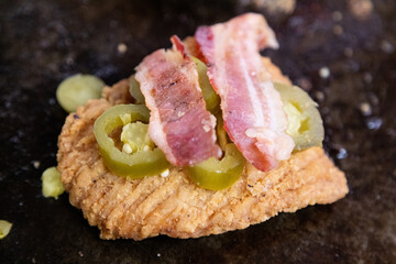crispy fried chicken patty with bacon and jalape&ntilde;o on a griddle