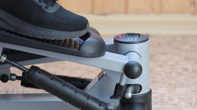 Workout on mini stepper exercise machine with digital display at home gym. Stepper tracks time, steps and calories while user performs cardio training in personal fitness space
