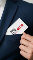 Close-up of a hand holding a card that says "Build Your Brand" inside a navy suit pocket, symbolizing business growth and branding strategies.  Mockup for marketing concepts.