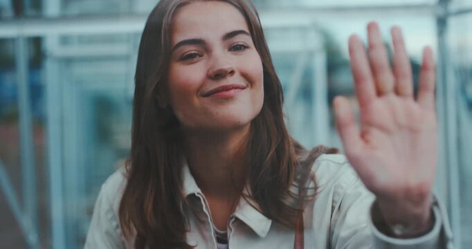 Beautiful young woman smiling inside transparent cabin with hand on glass holding coffee and instant camera, tilt shot from face to hand