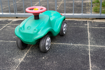 A bright blue and green children's toy car stands on a playground