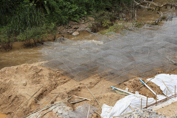 Groundwork preparation with wire mesh over sand for riverbank soil stabilization