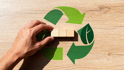 Hand placing blocks on recycling symbol