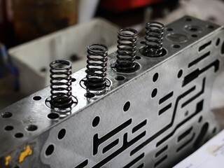 A close-up view of a komatsu valve body, featuring several dark springs and intricate internal pathways, suggesting maintenance or assembly.