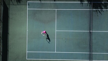 Aerial drone footage captures a female tennis player practicing on a hardcourt, highlighting dynamic movement, skill development, and dedication in a professional sports setting.