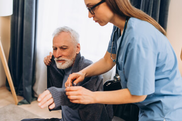 Obraz premium Nurse assisting senior man dressing home care