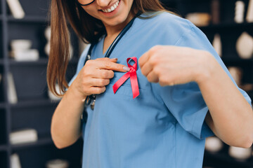 Healthcare worker showing pink ribbon for breast cancer awareness