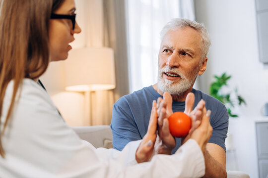 Doctor helping senior man with rehabilitation therapy ball