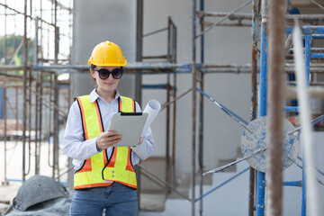 Female engineer in safety vest and helmet using tablet for construction site assessment, representing modern project planning, data management, and digital transformation in civil engineering.