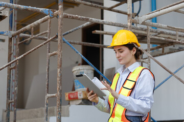 Female engineer in safety vest and helmet using tablet for construction site assessment, representing modern project planning, data management, and digital transformation in civil engineering.