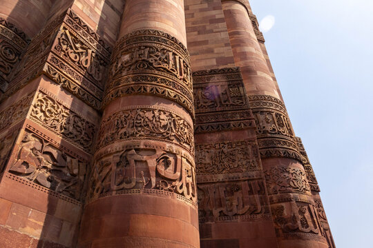 Detailed close-up of ancient Arabic and Persian inscriptions carved on the red sandstone pillars of Qutub Minar, Delhi, India, highlighting intricate heritage architecture and artisan craftsmanship.