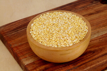 Bowl of organic mung dal - yellow gram on wooden board 