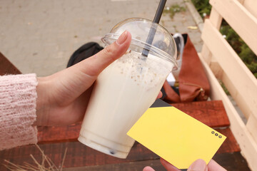 Hand holding plastic cup with cold milkshake
