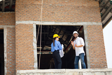 blue print interior design : Caucasian woman Architects and Hispanic men contractor working together inside building under construction site. Engineering in safety harthat helmet. Engineering team