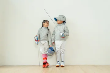 Selbstklebende Fototapeten Entspannung ฺAsian brother and sister with fencing sport uniform stand beside  also look at face and smile to relax during practice for competition.  © narong