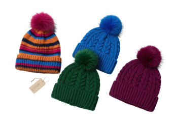 Four luxurious knitted winter hats with plush pom-poms: multi-striped, cobalt, forest green Aran, plum cable knit, on transparent studio background. Concept of elegant winter fashion