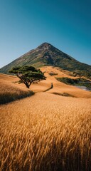 A solitary tree stands sentinel amidst a golden wheat field, with a majestic mountain rising majestically in the background.