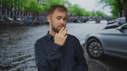 Man points finger at parked car on street in amsterdam canal area, visible pointing gesture and beard; curiosity travel.
