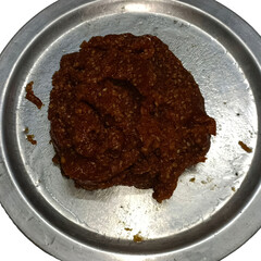 Traditional Indian sweet made with jaggery and sesame seeds, rich in flavor and texture, served on a steel plate. A rustic, homemade dessert enjoyed during festivals and winters.