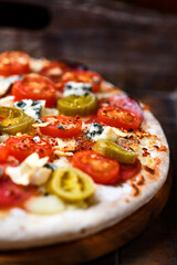 Pizza with salami, jalapeno pepper, cherry tomatoes and mozzarella cheese. Soft focus.	