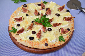 delicious pizza with figs, cheese, olives and herbs close up 