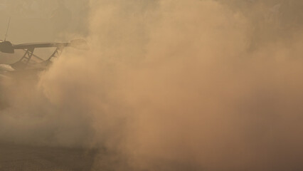 Car spoiler emerging through dense smoke during drift show, dramatic motorsport scene.