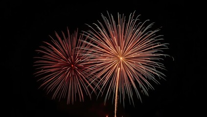 Two radiant firework bursts of vibrant orange, red, and white colors illuminate a dark night sky during a festive celebration.