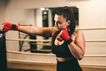 Female boxer practicing punches in a gym during a training session to improve skills and strength