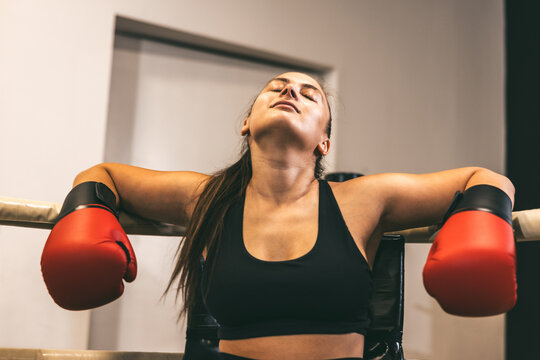 Female boxer resting after intense training session in gym, showcasing determination and resilience during workout - Powered by Adobe