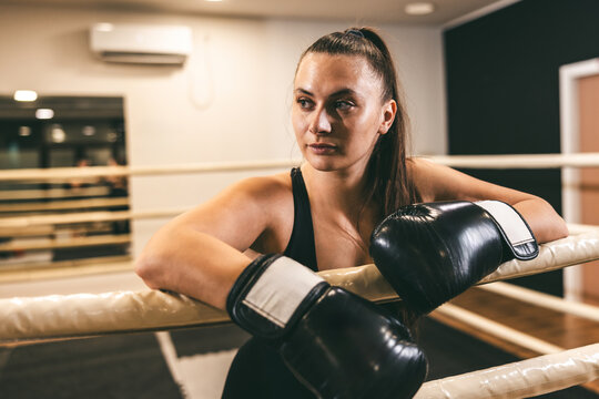 Boxer resting in the gym, preparing for training session in a well-lit boxing ring