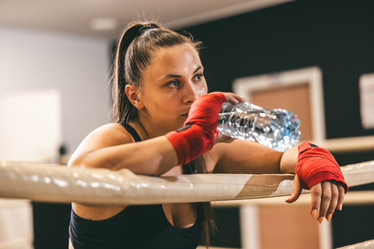 Female boxer resting and hydrating in training session at gym