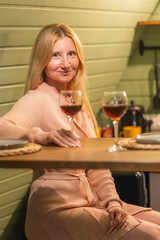 A beautiful woman drinks wine in the kitchen of a private home