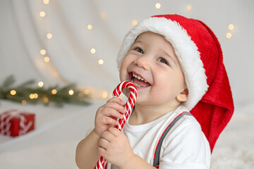 Happy baby in Santa hat with candy cane, Christmas joy.