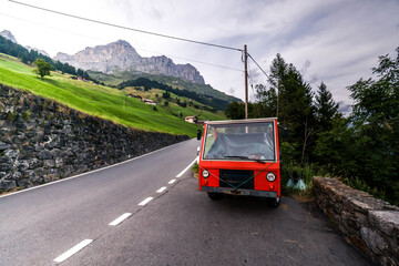 Obraz premium auto rojo en montañas alpinas suizas en la carretera