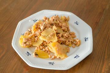 Moussaka, a dish of potatoes and minced meat in a white plate on the table
