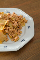 Moussaka, a dish of potatoes and minced meat in a white plate on the table