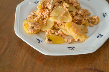 Moussaka, a dish of potatoes and minced meat in a white plate on the table