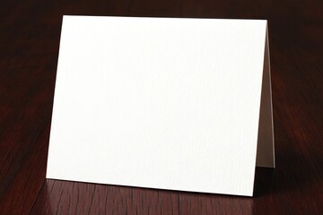 Blank white folded card on a dark wooden surface