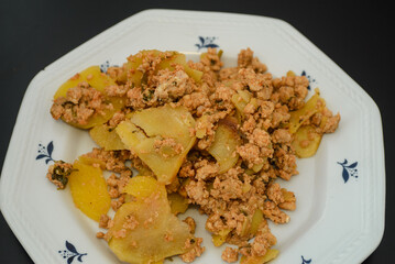 Moussaka, a dish of potatoes and minced meat in a white plate on the table