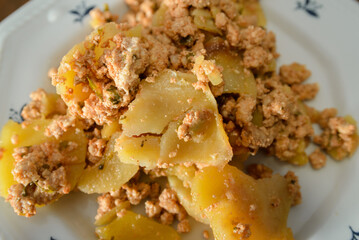 Moussaka, a dish of potatoes and minced meat in a white plate on the table