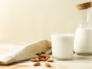 Glass and Bottle of Milk with Almonds on Wooden Board