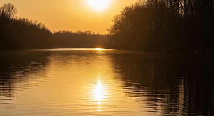 Obraz premium A serene golden hour over a tranquil river, with the sun's reflection shimmering on the calm water surface