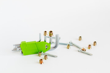 Green hex key wrench set with screws and threaded inserts on white background, construction tool equipment.