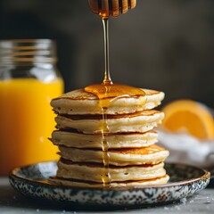 Photo of pancakes stacked high with honey drizzle, served with orange juice for breakfast