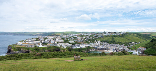 couple on bench at viewpoint above harbour and village of port isaac in cornwall